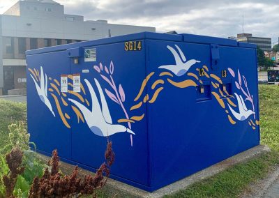 Deep Blue painted power box with white painted birds on it carrying pink branches.