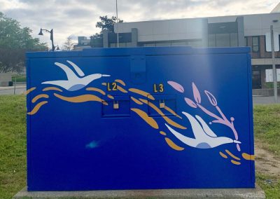Deep Blue painted power box with white painted birds on it carrying pink branches.